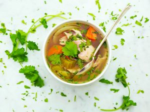 A bowl of chicken soup and vegetables in a clear broth - an EBS recipe