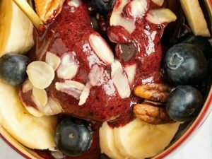 A bowl of frozen blueberries, bananas, pecans and chopped nuts.