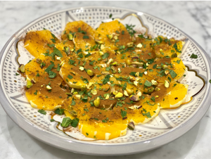 Sliced oranges on a pretty plate with spices and herbs, showing a recipe in an anti-inflammatory diet plan.