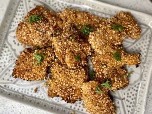 A tray of chicken bites coated in anti-inflammatory ingredients, sprinkled with herbs