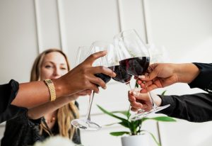 People raising a toast with glasses of red wine