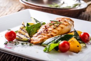 A plate of chicken and grilled vegetables.