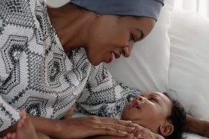 Woman staring down at her baby, with a huge smile on her face.