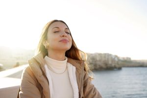 Female, closed eyes, facing the sun, smiling.