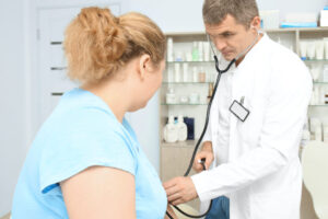 Doctor measuring blood pressure of overweight woman in hospital