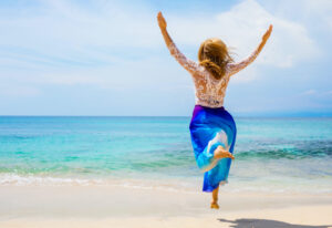 Woman having great happy life, jumping for joy on the beach