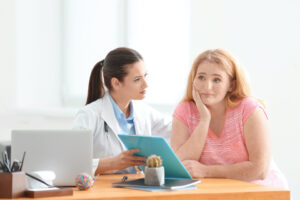 Young female doctor consulting overweight woman in clinic