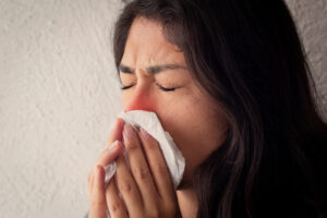 Female with a red nose sneezing - an acute inflammatory reaction.