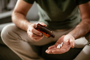 Man, face not seen, holding an antidepressant pill bottle