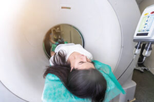 Pretty, young woman goiing through a Computerized Axial Tomography CAT Scan medical test examination in a modern hospital