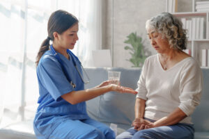 A female doctor handing a painkiller to her female patient who looks in pain.