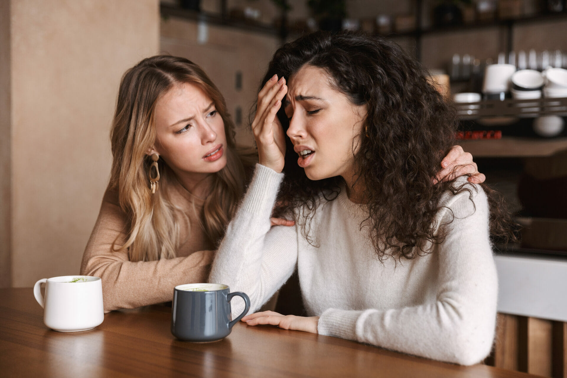 Depressed, anxious female being comforted by her female friend.