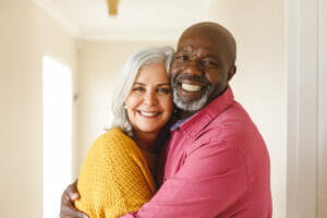 A man and woman cuddling and smiling at the camera. 