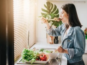 woman standing eating salad