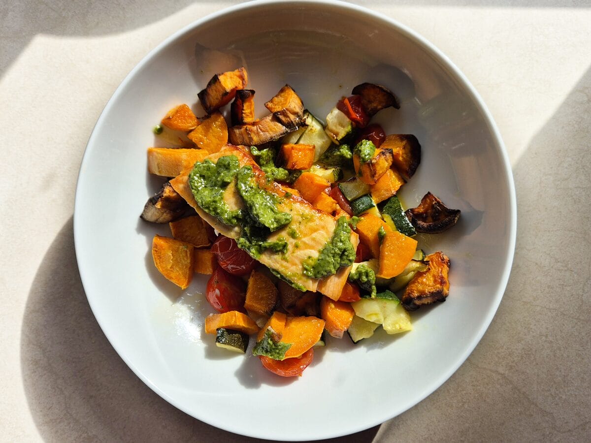 bowl of pesto salmon and roasted vegetables from a pesto salmon traybake recipe