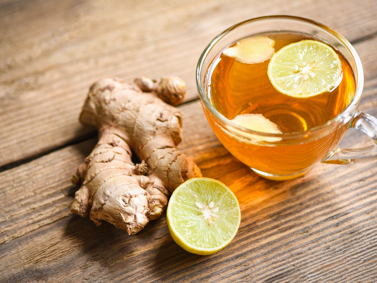 a cup of ginger tea with lemon slices and a side of ginger root